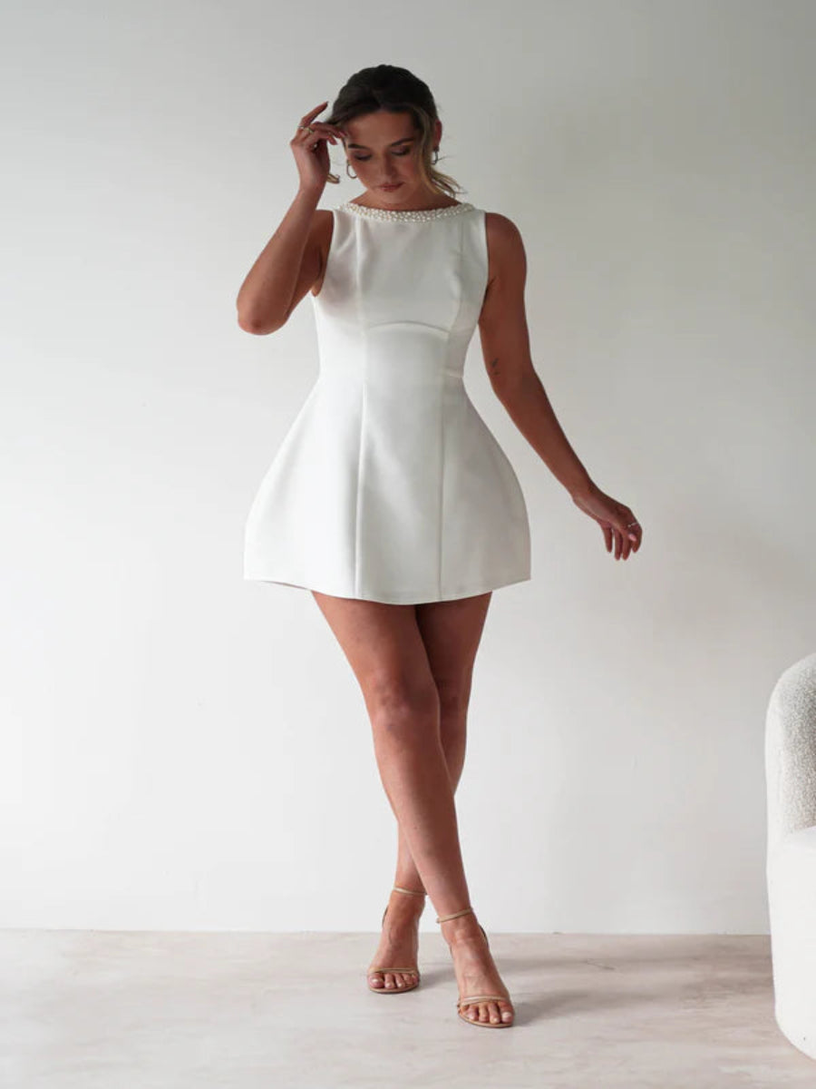 Woman wearing a white dress against a plain background