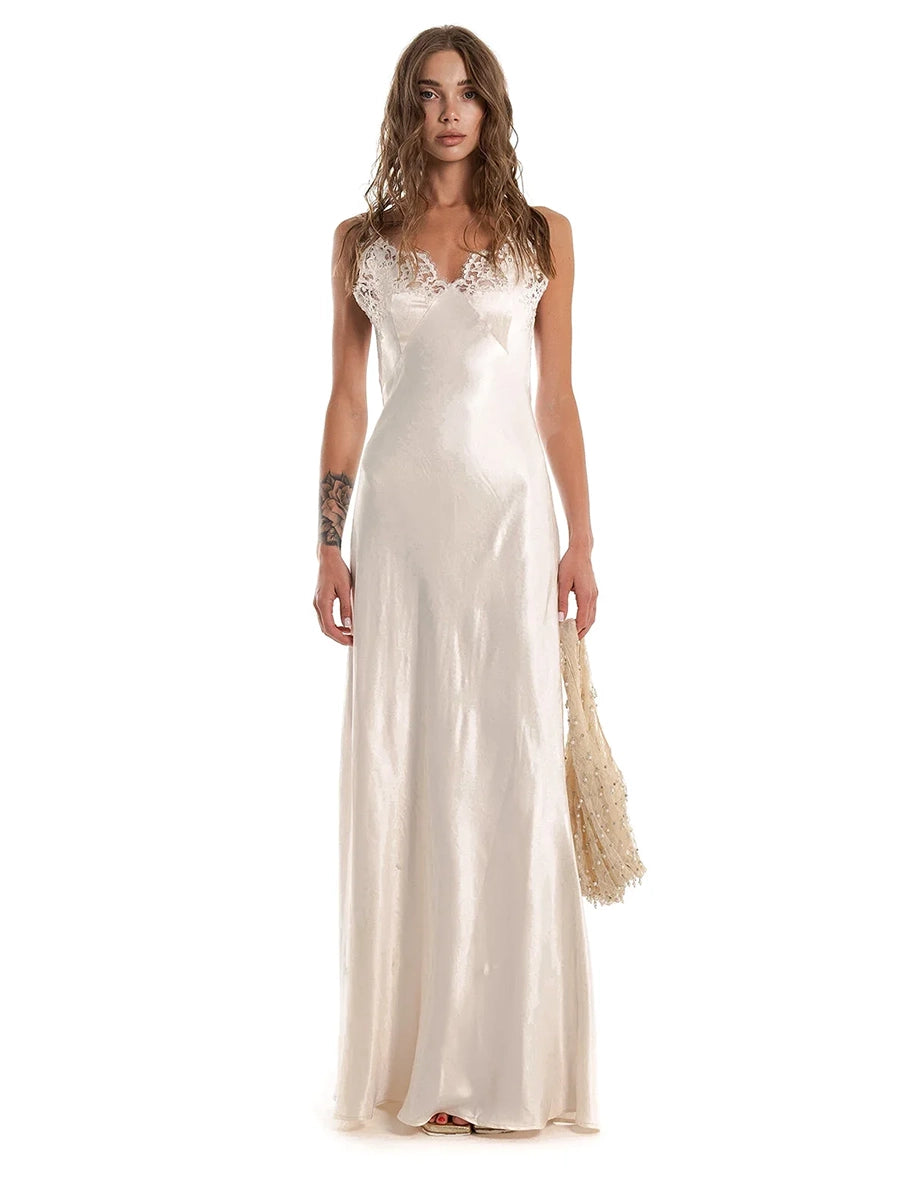 Woman wearing a long white dress with lace detailing on a white background